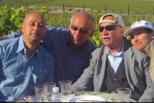 Four people sitting outdoors with arms around eachother