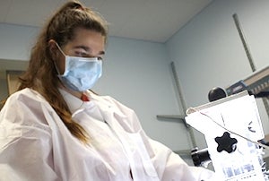Person standing in lab coat and face mask
