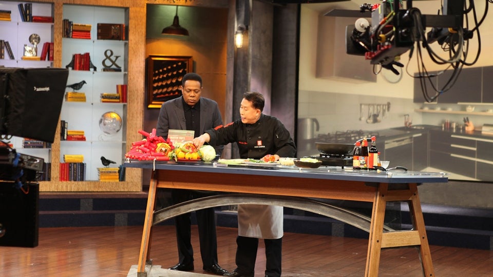 Martin Yan sets up for a live cooking segment in a television studio.