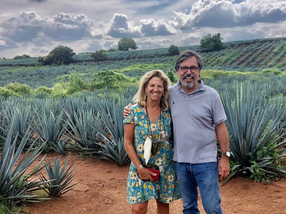 Two people stand in front of agave plants.