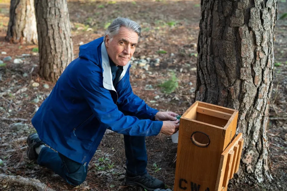 Professor John Eadie kneels by wood duck box
