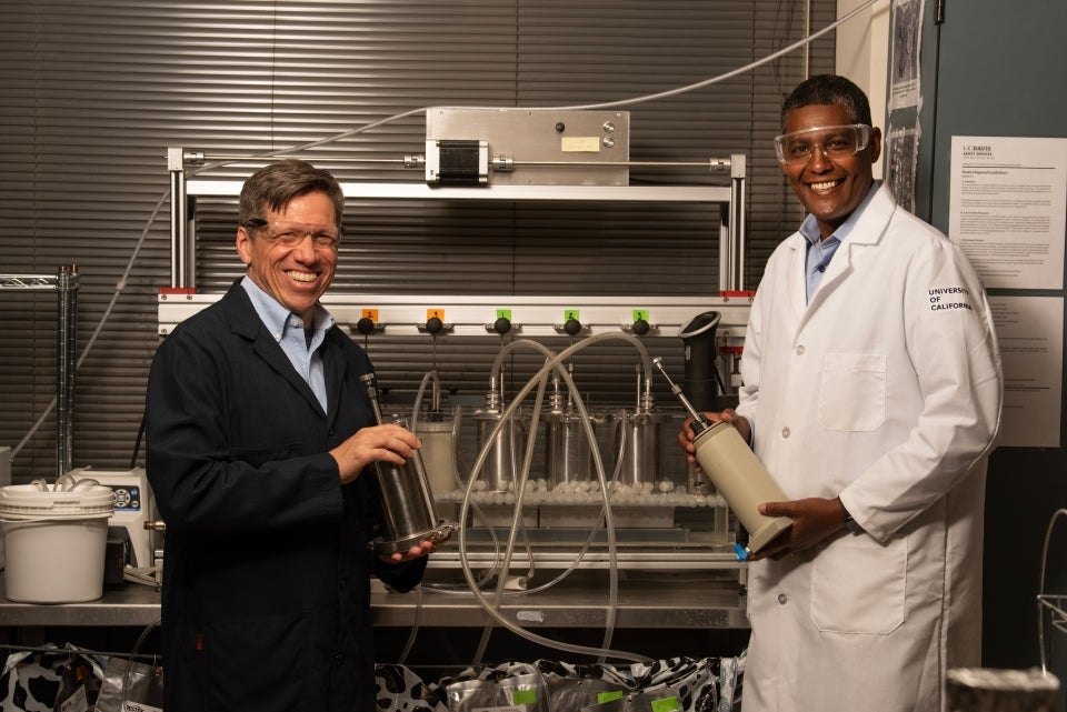 Matthias Hess, left, and Ermias Kebreab, right, stand in front of a system that mimics a cow's rumen and allows Hess to study gas-producing microbes.