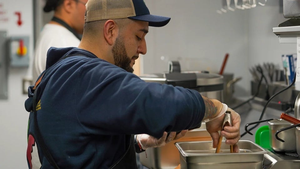 Jesus &#34;Sal&#34; Ramirez, food truck coordinator for AggieEats serves food in the kitchen of the food truck.
