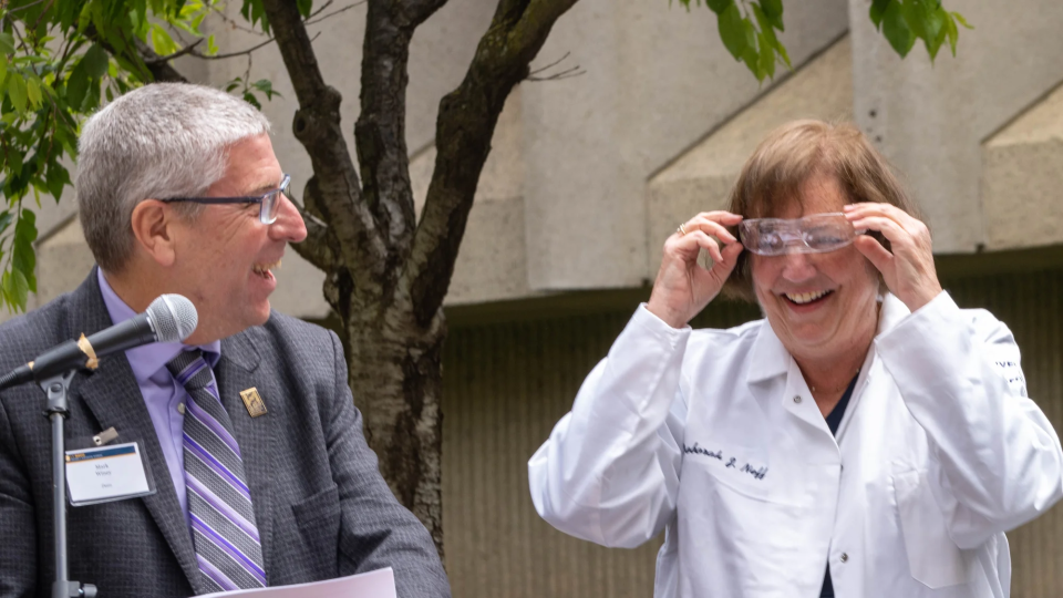 Deb Neff adjusts her safety glasses, after receiving them and a personalized lab coat from Dean Winey, left, Chancellor May and Professor McAllister, during a University Foundation Board luncheon outside Green Hall. (Sasha Bakhter/UC Davis)