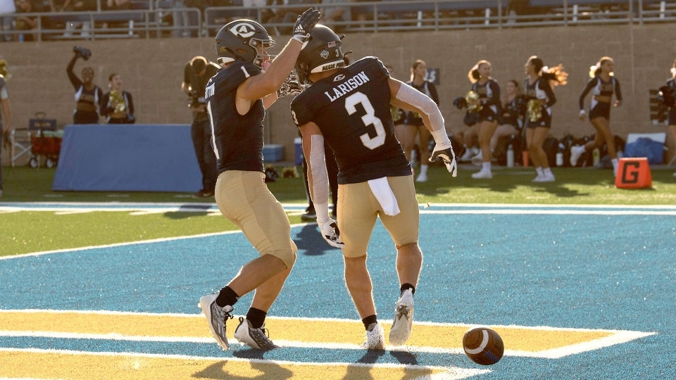 two UC Davis football players in uniform celebrating a touchdown
