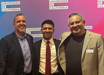 Sergio Maciel and Pablo Reguerin pose with a campus administrator in front of a Universidad de California backdrop.