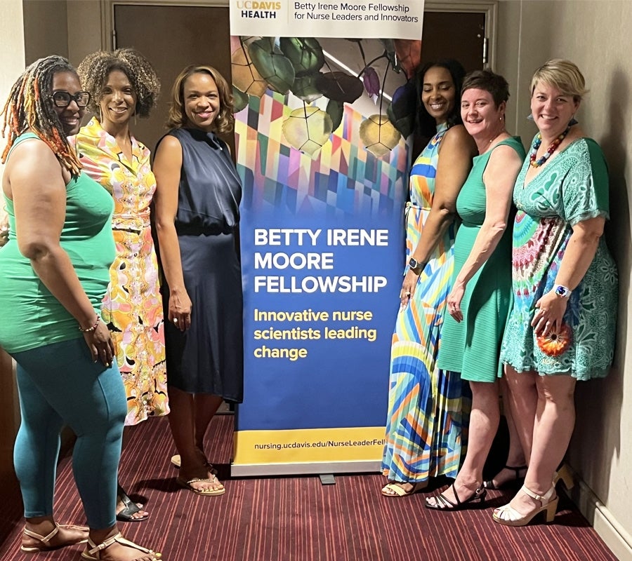 A group of fellows pose with a retractable banner promoting the Betty Irene Moore fellowship.