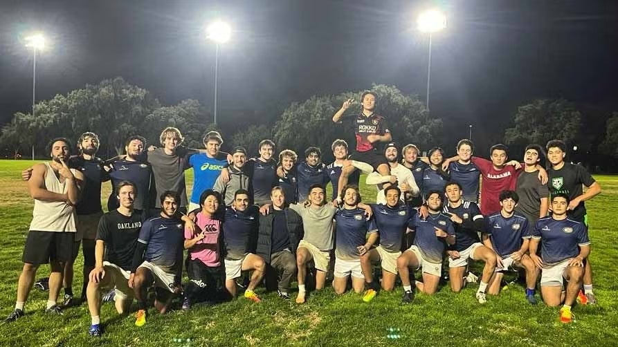 A group of soccer players pose on the field after a game.