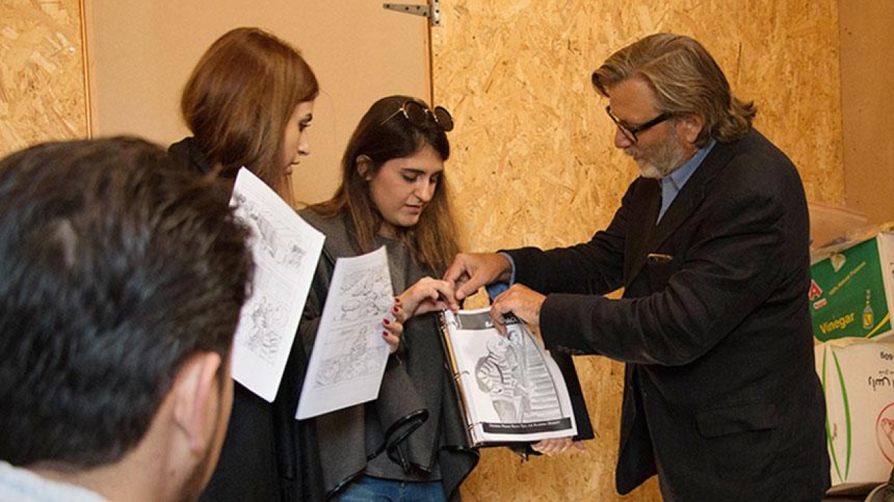UC Davis professor Keith David Watenpaugh, right, and two trained guides from the American University in Beirut use a comic book to explain Article 26 Backpack at a refugee camp in Lebanon as Jihad Qusanyeh looks on. (Liz McAllister/UC Davis) Man and two trained guide show comic book.