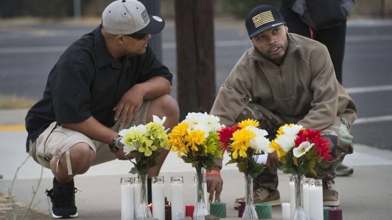 Two men at a memorial with flowers 