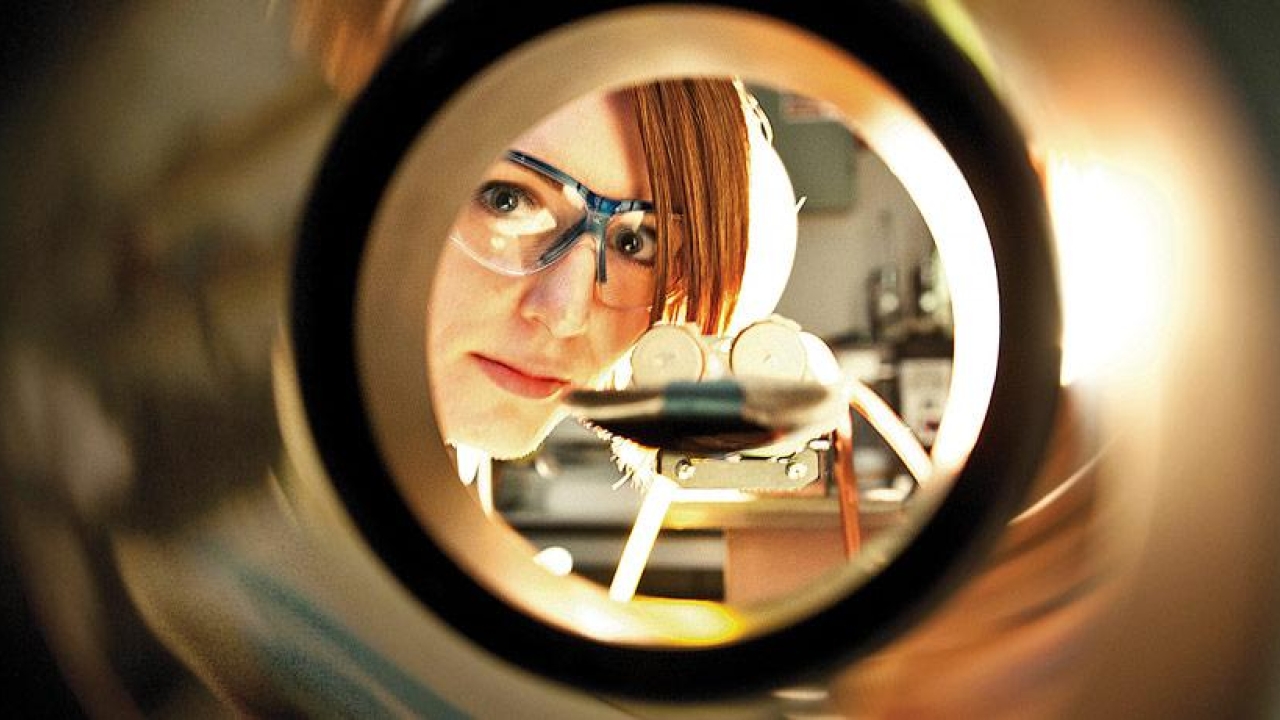 Medical scientist looking through a circular piece of equipment.