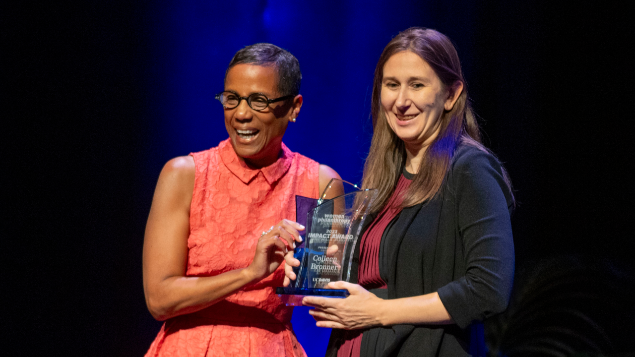 Dr. Colleen Bronner accepts the impact award on stage next to LeShelle May.