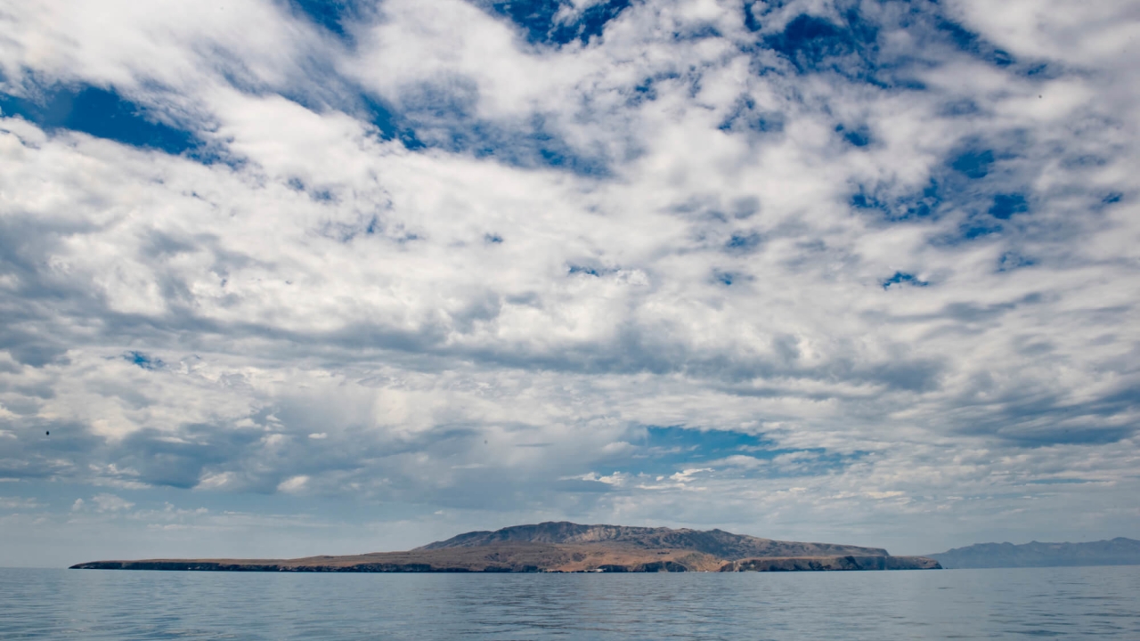Blue sky with clouds with a body of water and an island