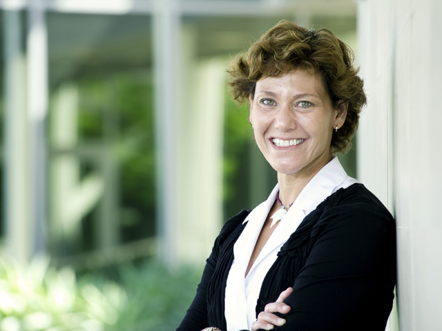 Kimberly smiling with crossed arms in front of the Graduate School of Management.