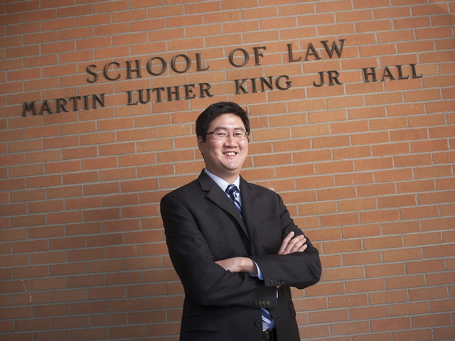 Peter Lee poses in front of the red brick entrance to Martin Luther King Jr. Hall