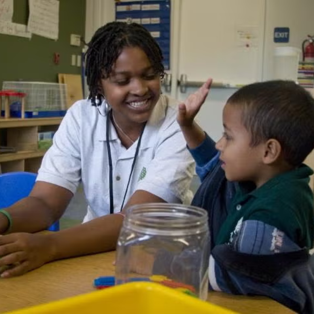 A teacher seated with a young student.