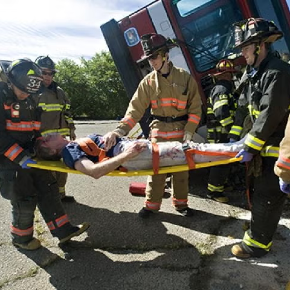 A group of medics and firefighters strap a patient onto a gurney.
