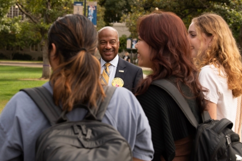 Chancellor May speaking casually to a group of students on the Quad.