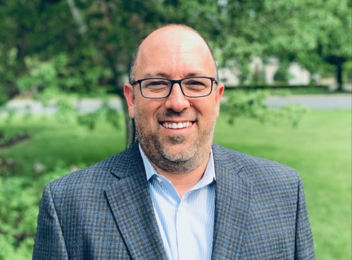 Chris Sikorowski's headshot in front of a blurred background with trees and grass.