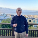 Bob Blumberg at his home in San Francisco on the wooden deck overlooking rooftops with a view of the ocean and hills in the background.