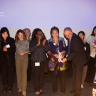 Maria Manetti Shrem and campus administrators at the ribbon cutting grand opening of the Maria Manetti Shrem Institute for Sustainable Design. They are joined on stage by design, fashion and textiles students.