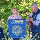 Philanthropists Sanford I. Weill and Joan Weill on a stage with Dean Mark Stetter, holding their dog Sweet Pea, and Vice Chancellor Shaun B. Keister